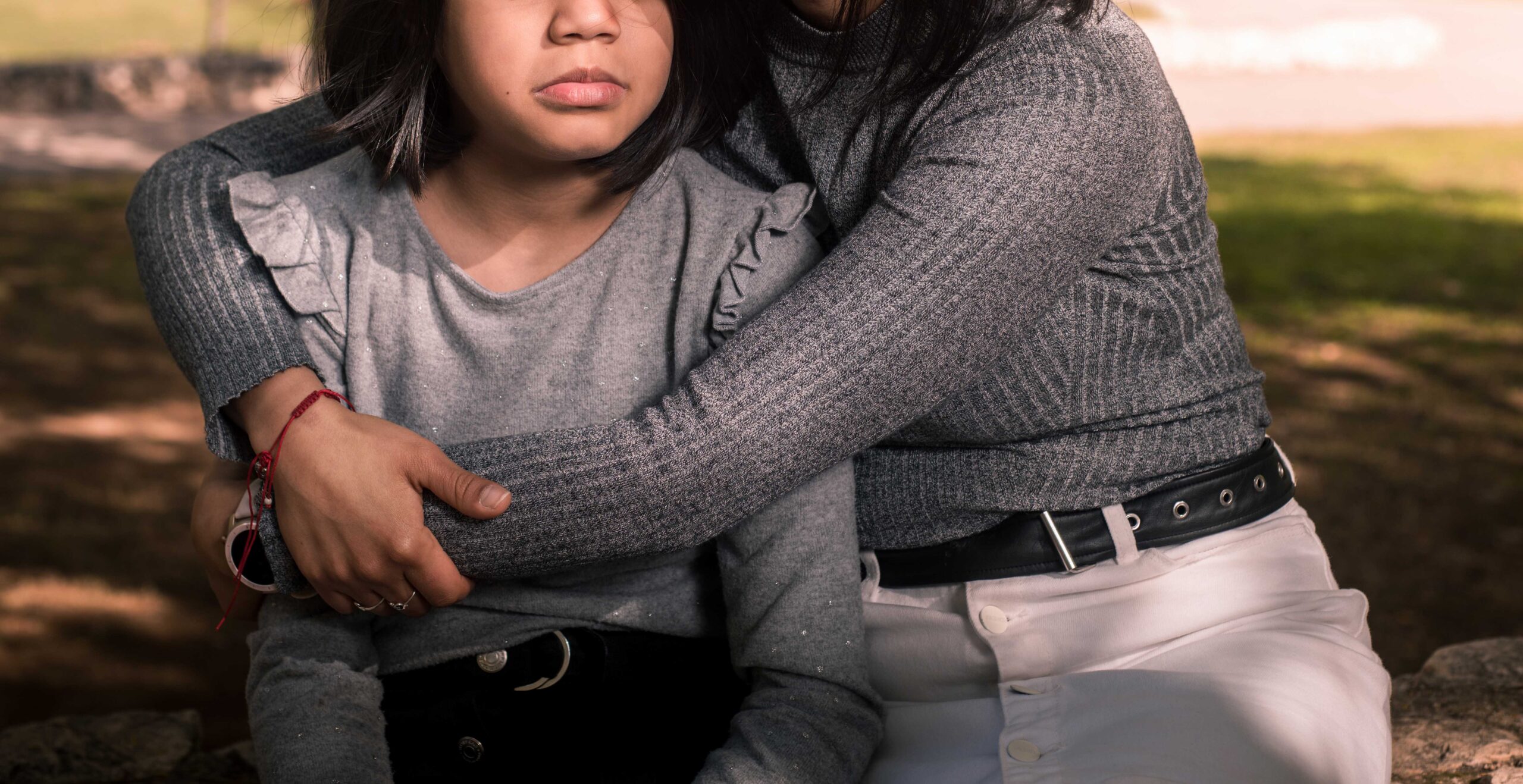 Young mother comforting her daughter outside at the park.