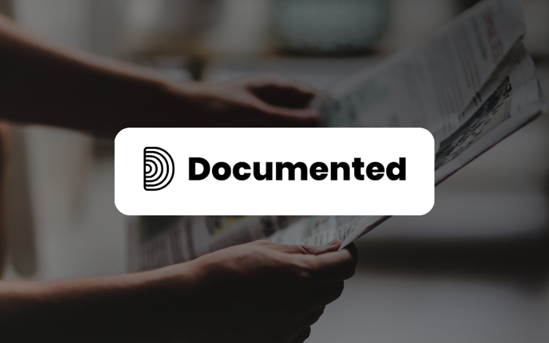 Background picture of someone holding a newspaper and a logo with the word "Documented".